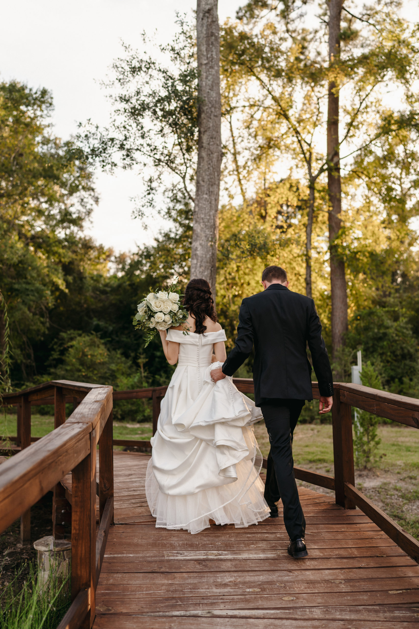 bride and groom walking over a bridge