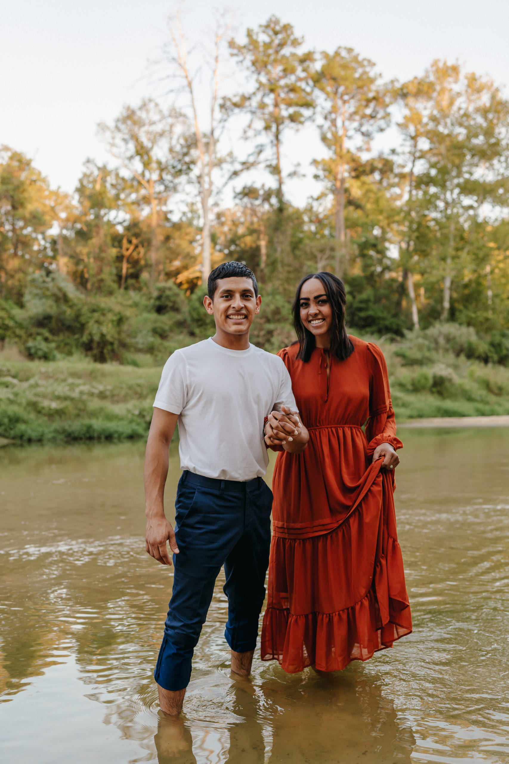 A couple smiling at the camera for their engagement session done by Angelina Loreta Photography in Houston, Texas.