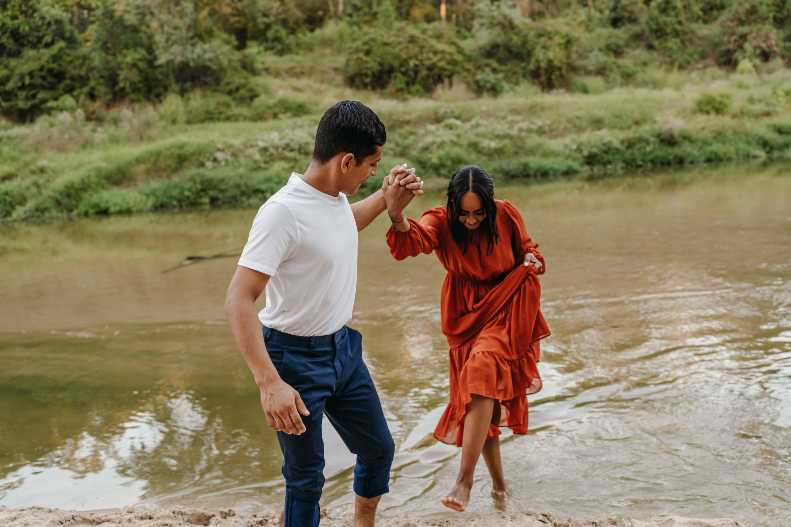 A couple stepping in the water for their engagement session done by Angelina Loreta Photography in Houston, Texas.