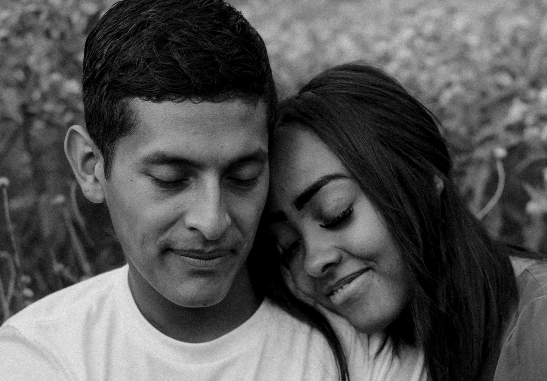 a black and white photo of a couple sitting in a garden for their engagement pictures done by Angelina Loreta Photography in Houston, Texas