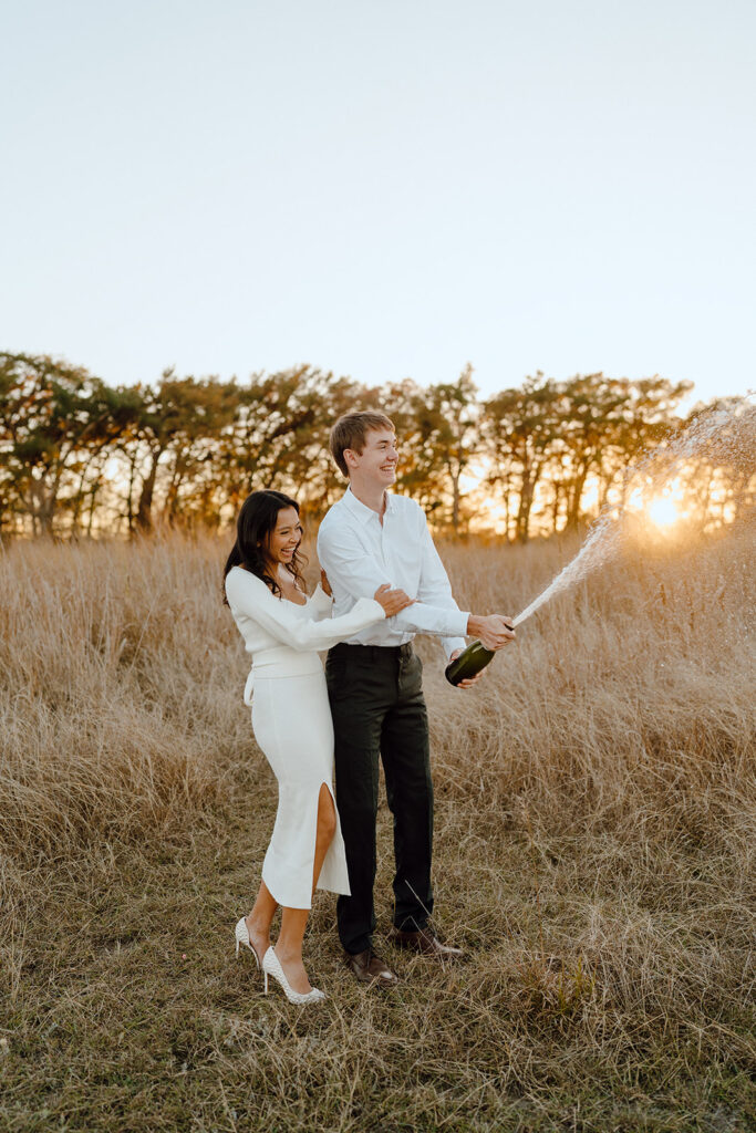 couple popping champagne during engagement session