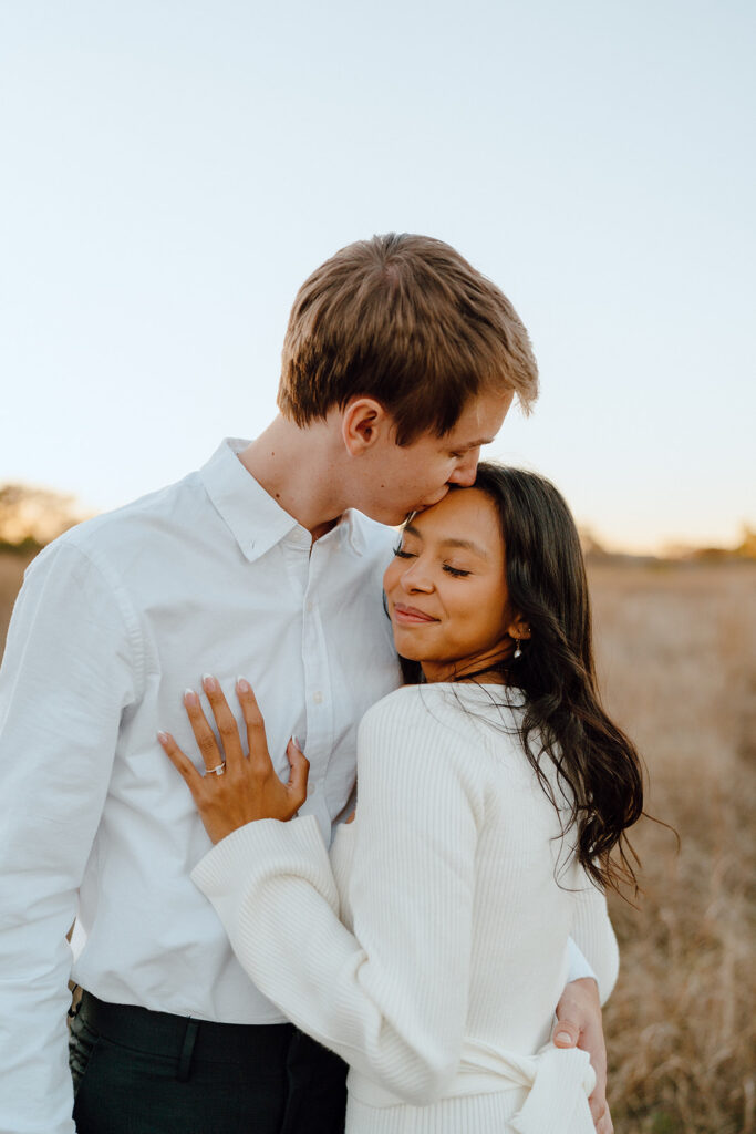 white neutral engagement photo outfits couple hugging and kissing