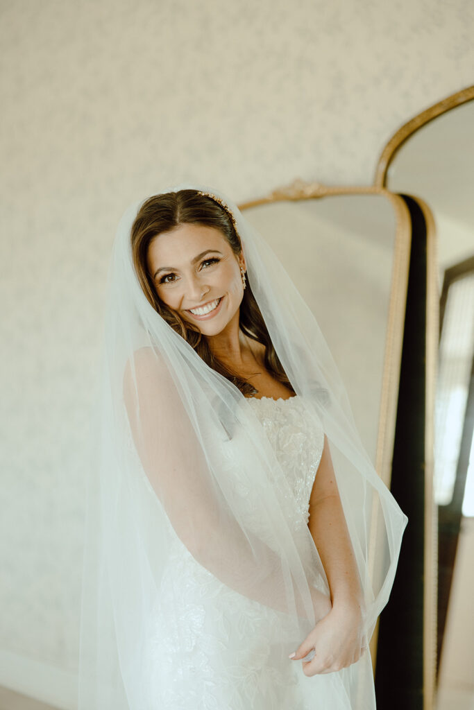 bride smiling and wrapping herself in veil