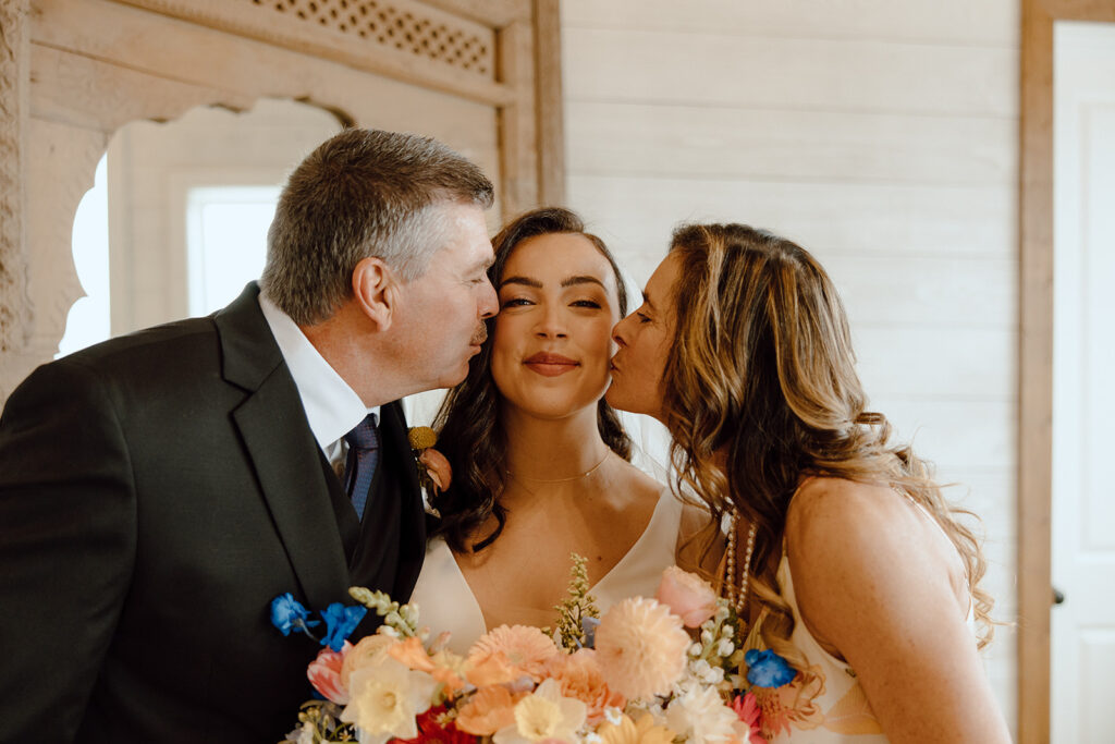 mom and dad kissing bride on the cheek before ceremony