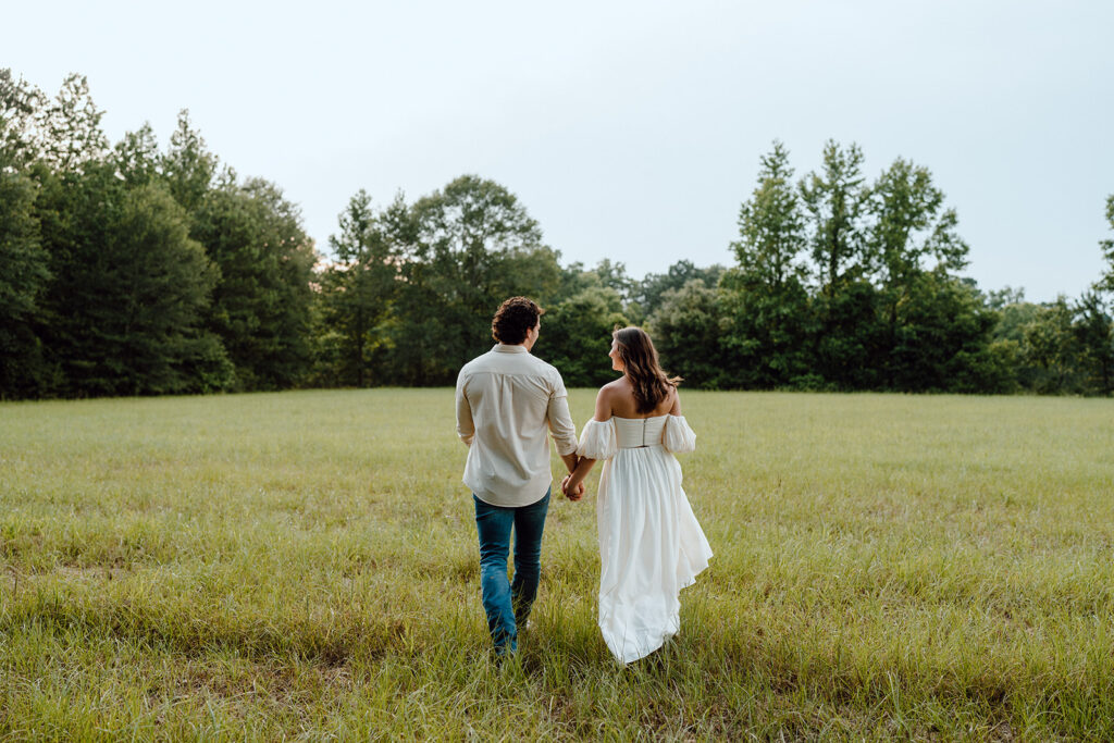 couple holding hands and walking away for field engagement photos
