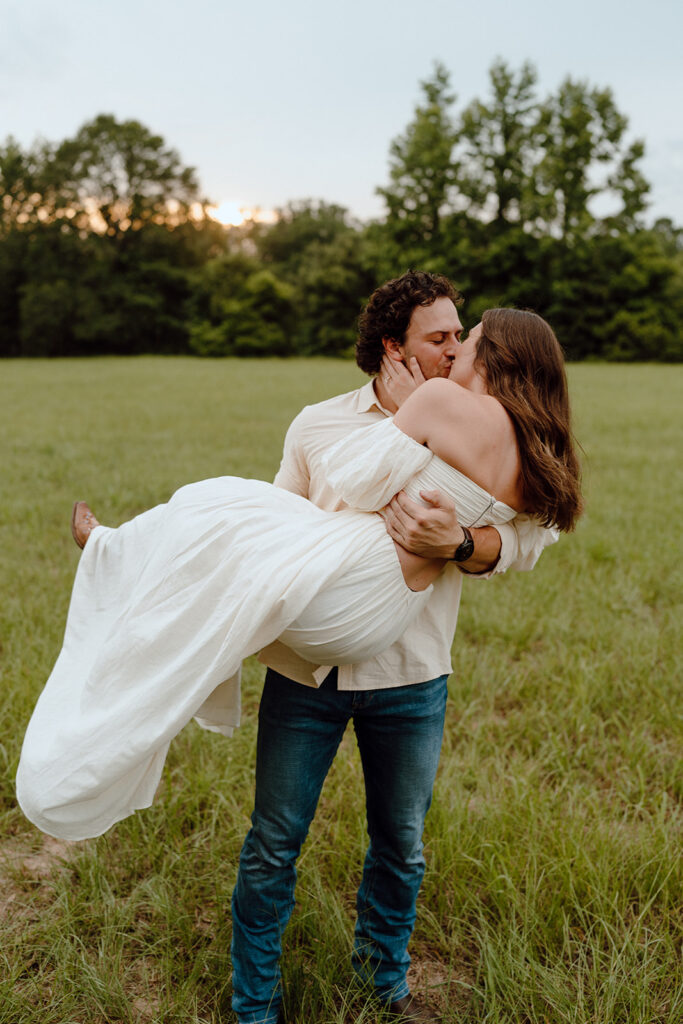 guy holding girl pose in open field outdoors