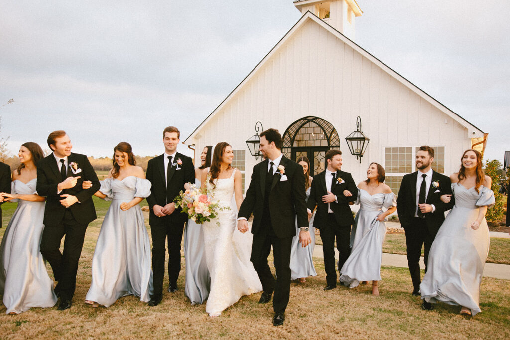 bridal party walking photos in front of barn venue