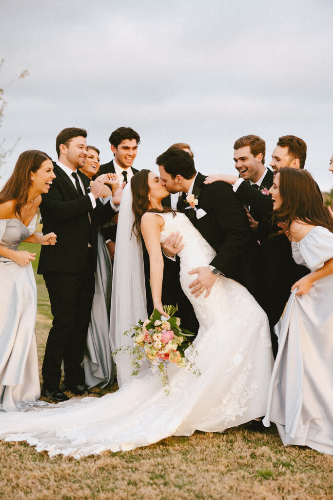 bride and groom kissing in the center of bridal party