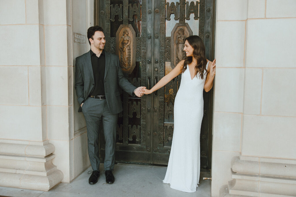 bride and groom smiling and holding hands in doorway