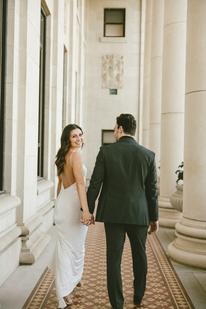 bride and groom smiling and walking away from camera