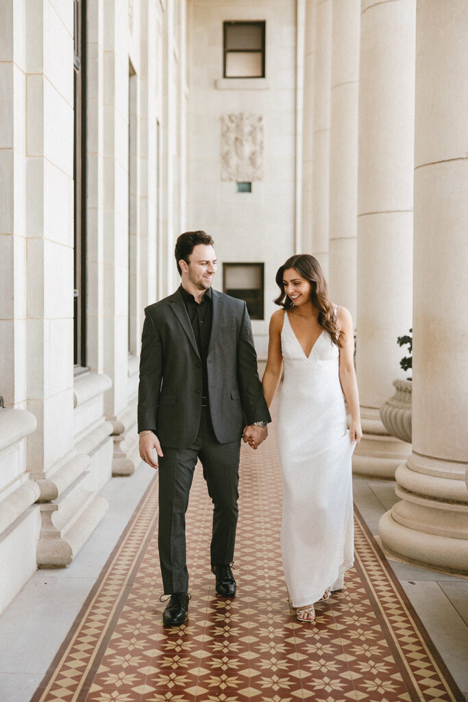 bride and groom holding hands and walking before rehearsal dinner photos