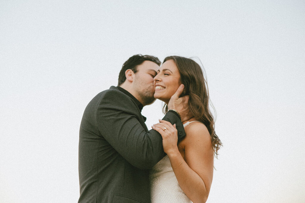 bride and groom smiling groom kissing bride's cheek