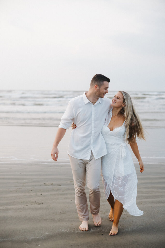 couple smiling and walking toward camera during engagement photoshoot