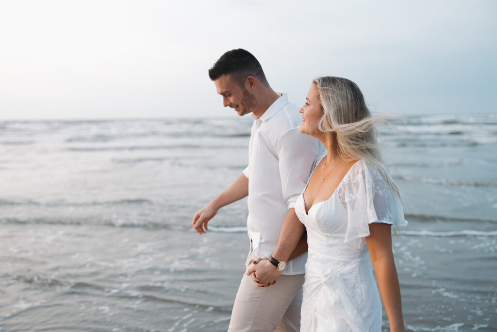 couple holding hands and walking on the beach