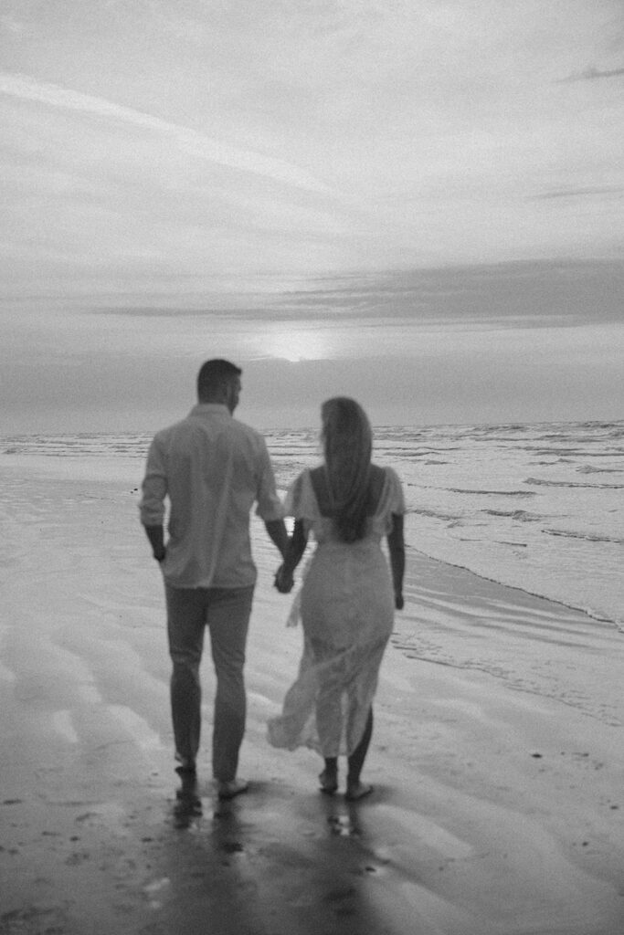 couple holding hands and walking on texas beach