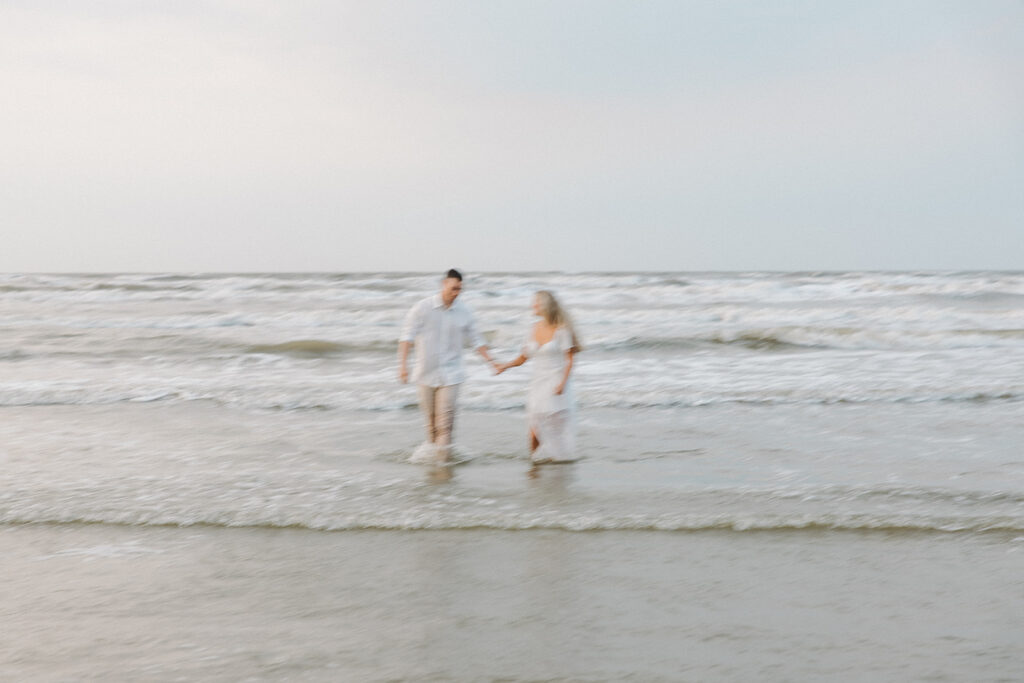 couple smiling and walking in the ocean blurry pictures