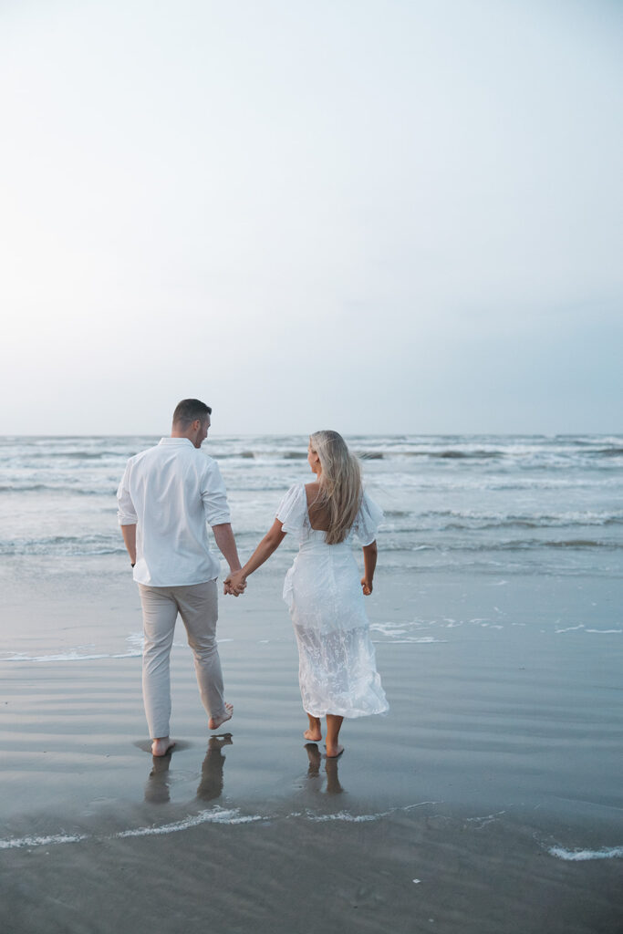 couple holding hands and walking on the beach in texas