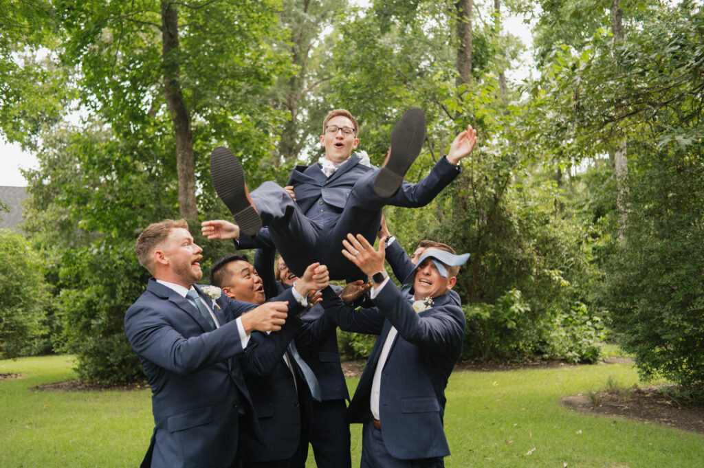 groomsmen tossing groom in the air candid bridal party photos