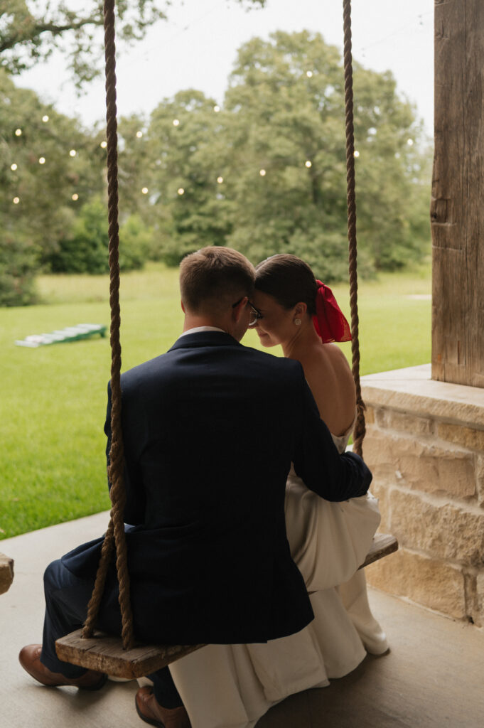 bride and groom sitting on porch swing