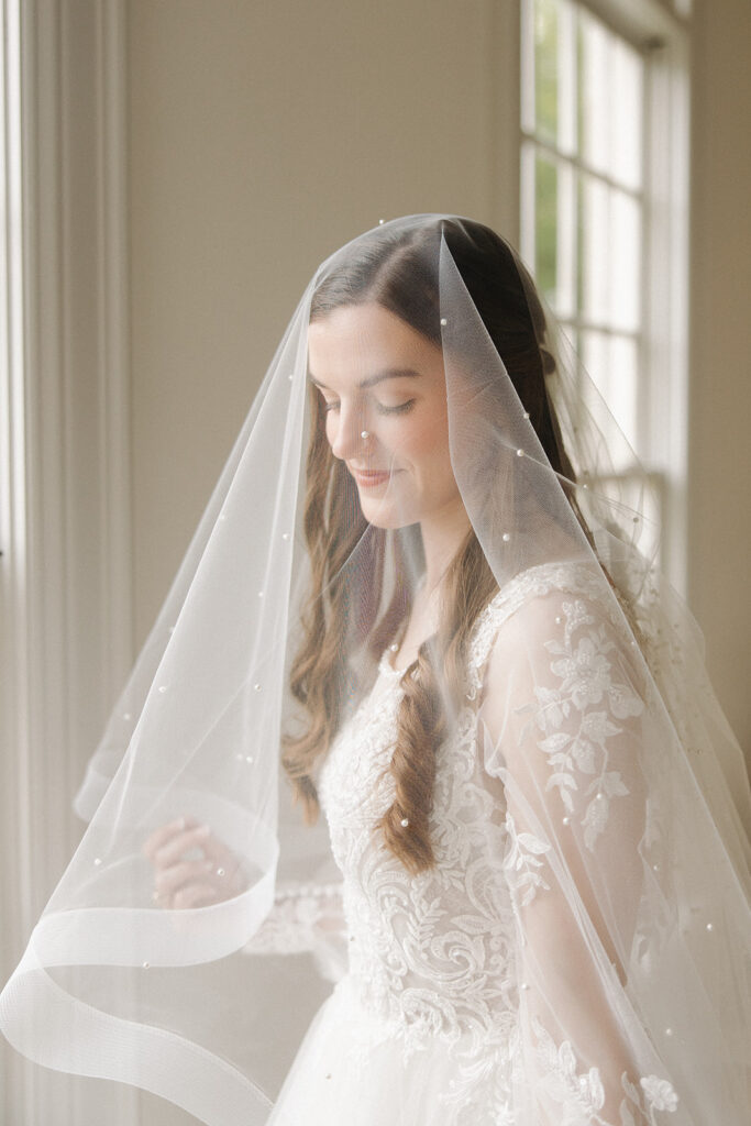 bride smiling underneath pearl detailed veil