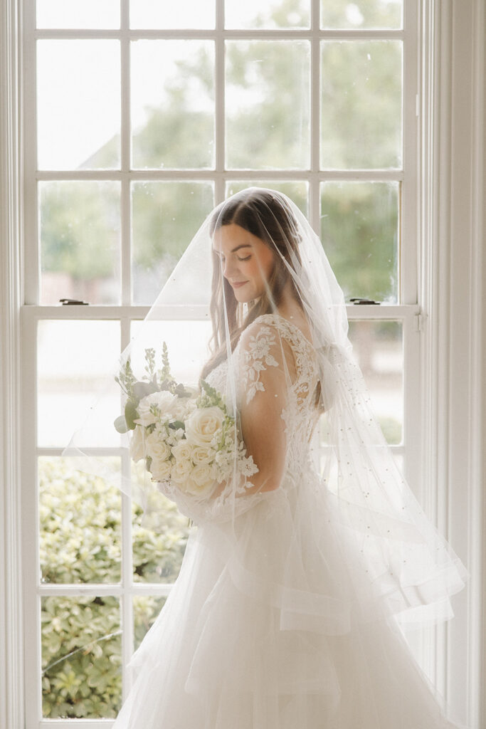 wedding photos in front of window with bride holding bouquet under veil