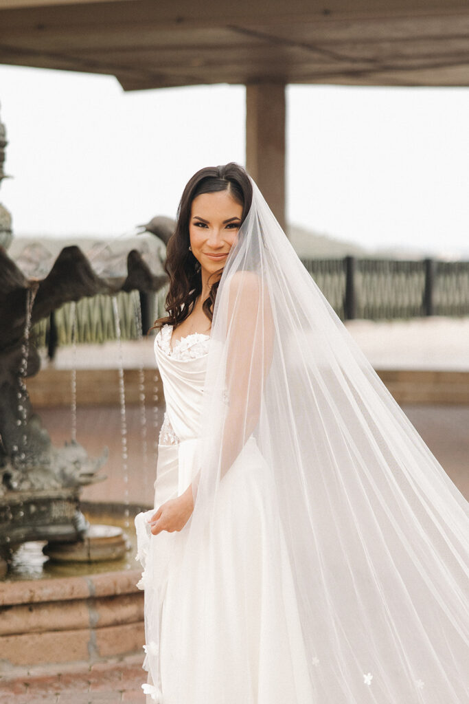 bride veil photos in front of elegant fountain