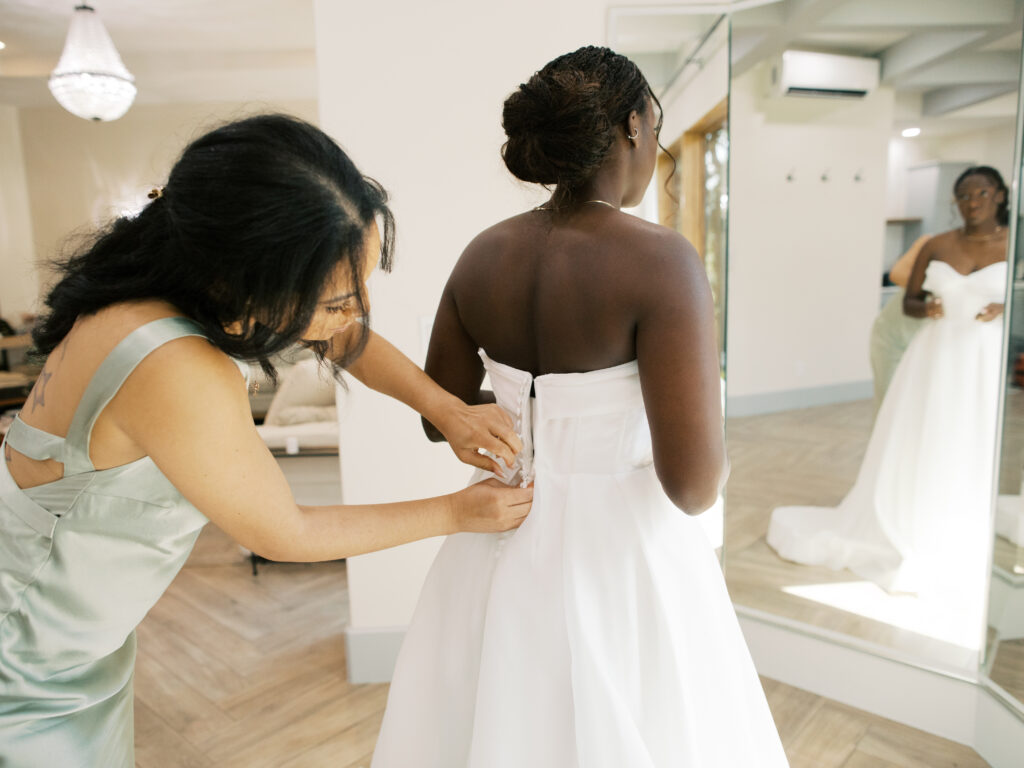 bride getting ready buttoning up dress