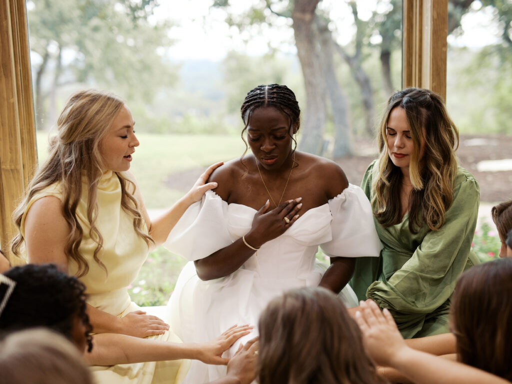 bridesmaids praying over bride before wedding