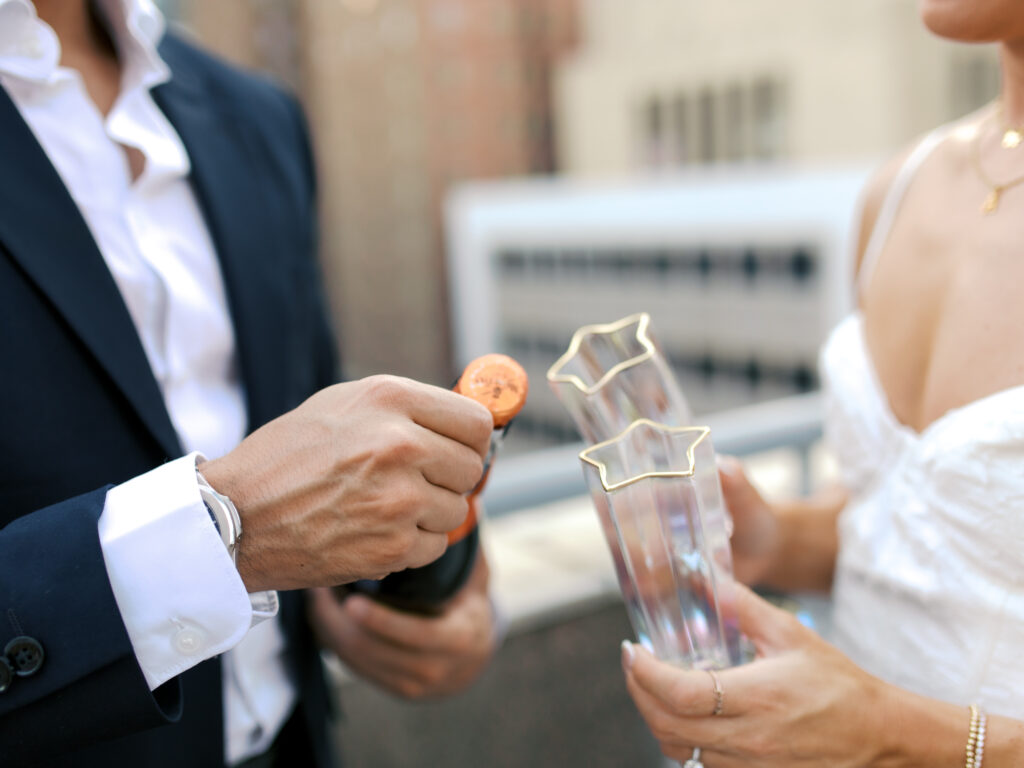 couple popping champagne during engagement session