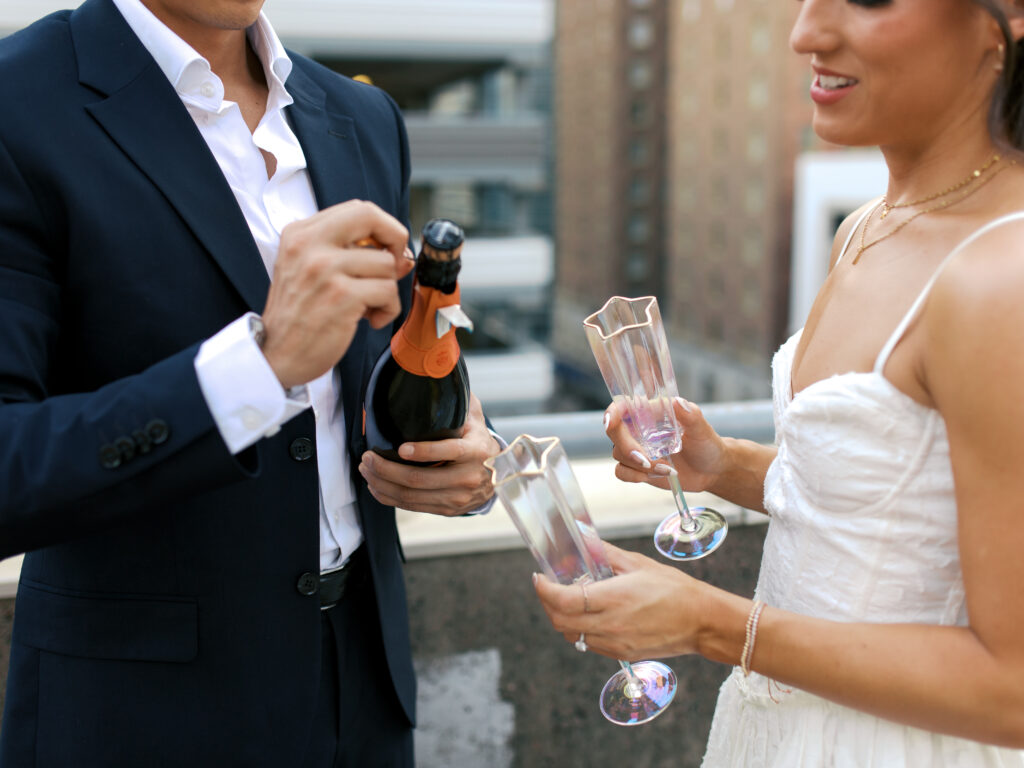 couple popping champagne during engagement session