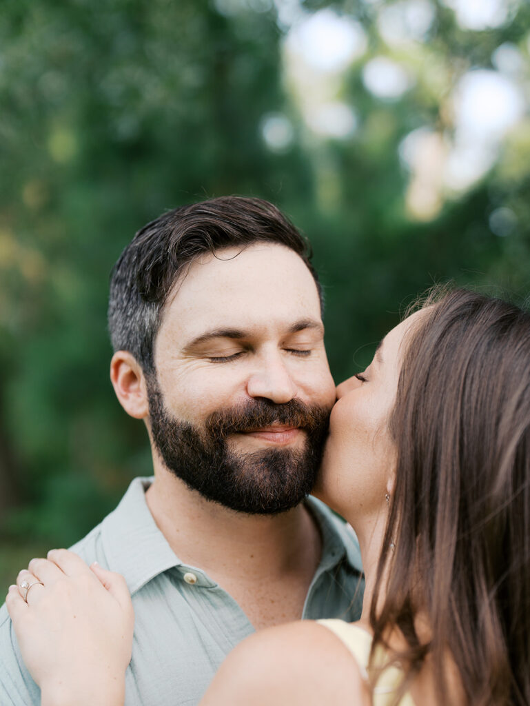 couple kiss on the cheek for engagement photos