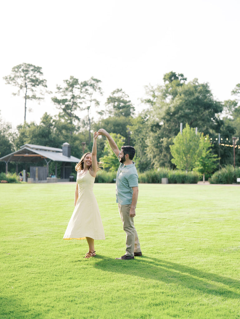 couple spinning and laughing at the park in houston