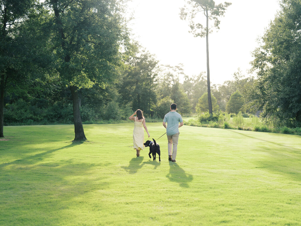 couple laughing and running with their dog