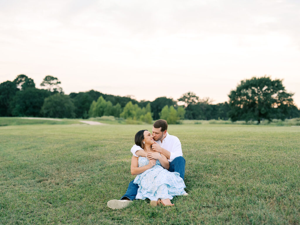 couple cuddling in a field during sunset