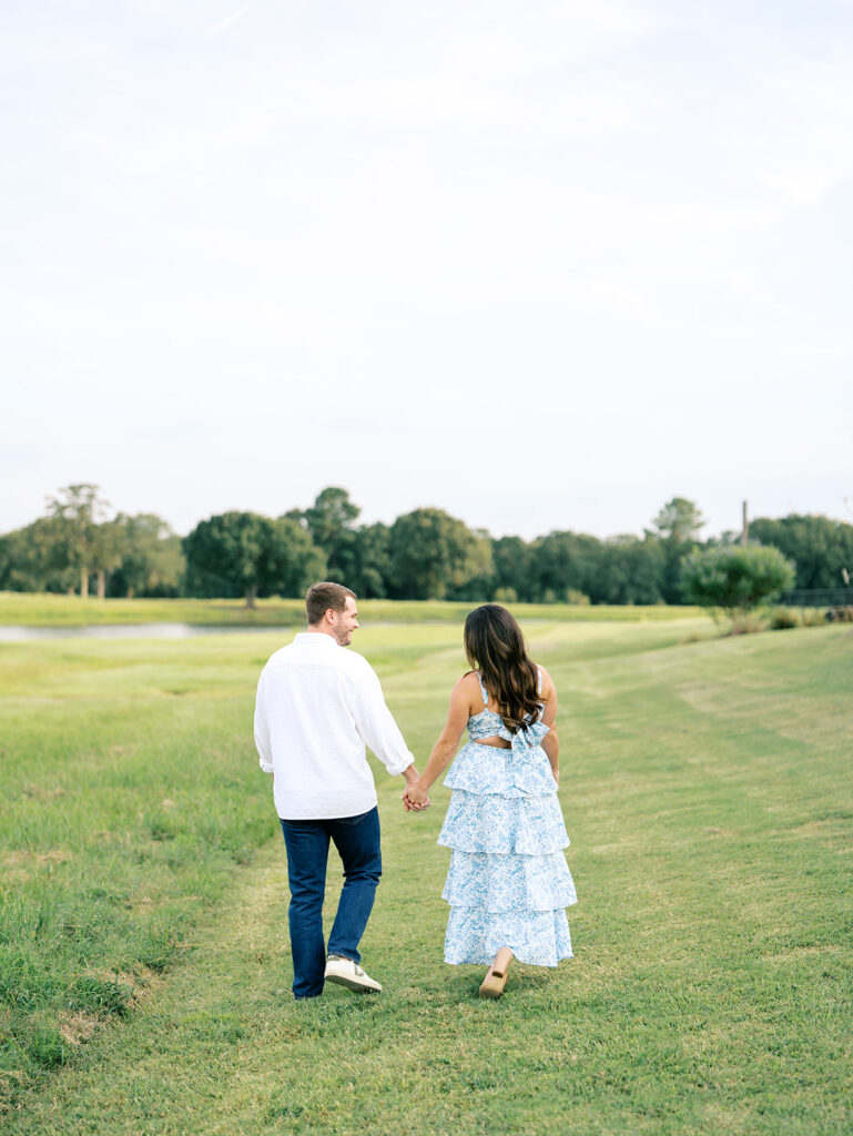couple holding hands and walking in a field