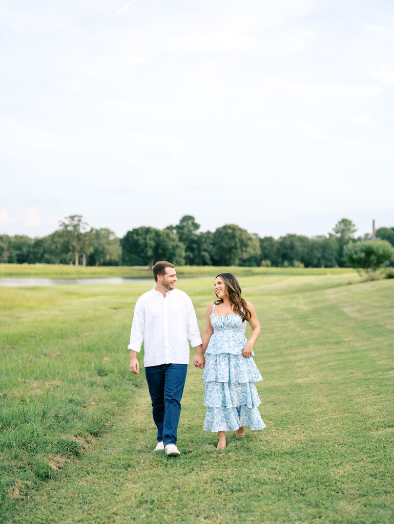 couple holding hands and walking in a field