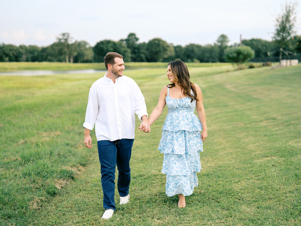 couple holding hands and walking in a field