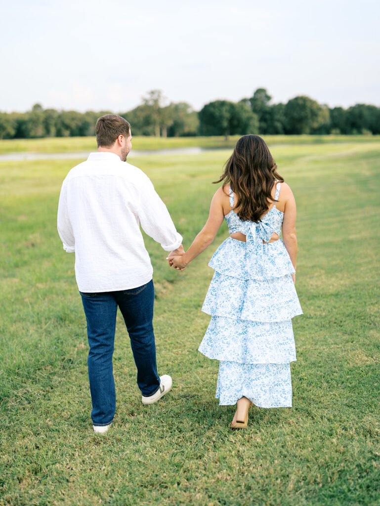 couple holding hands and walking in a field