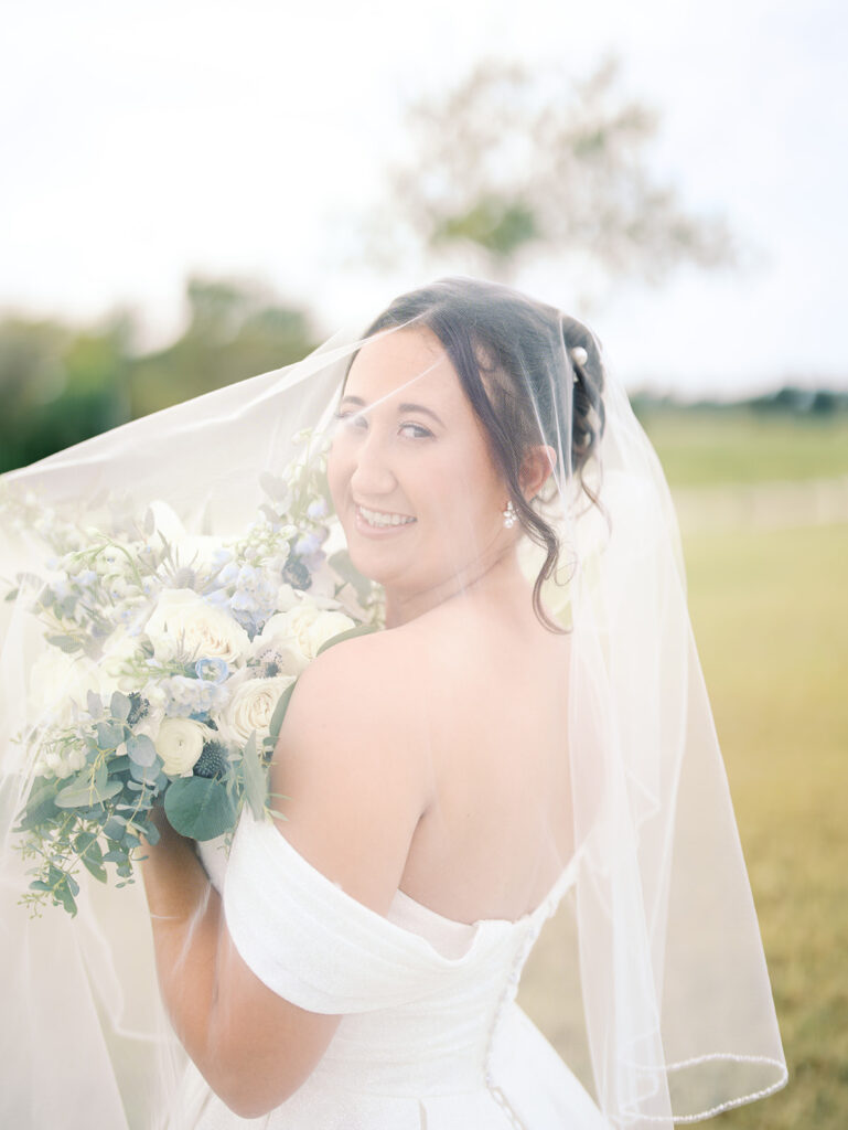bride smiling with her flowers under the veil