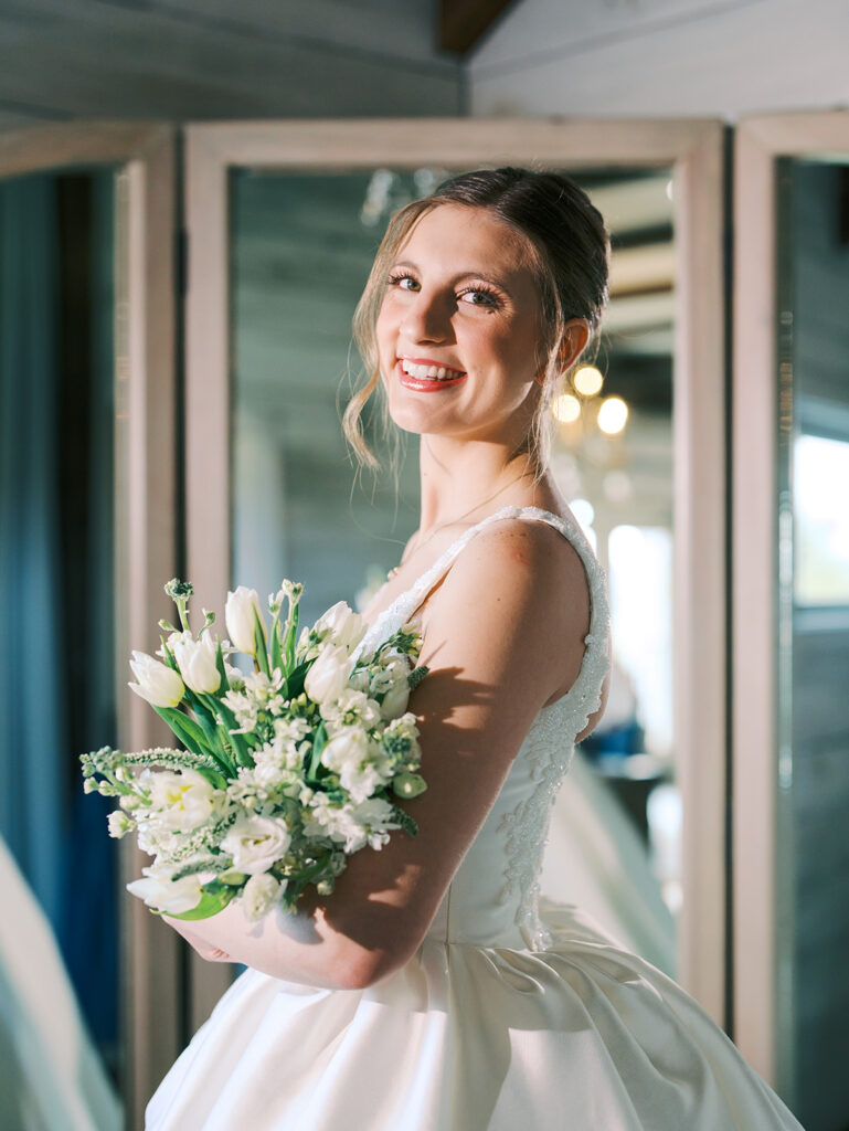 bride smiling at the camera while holding her bridal bouquet