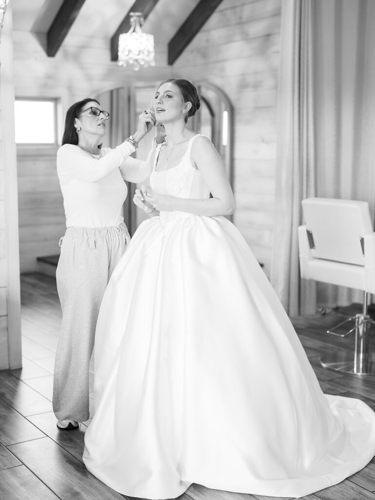 mom helping bride get ready for her bridal portraits in a black and white photo