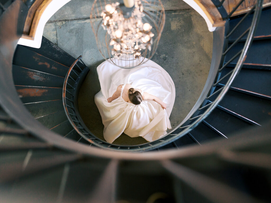 cinematic classy wedding photos of bride spinning a the bottom of spiral staircase