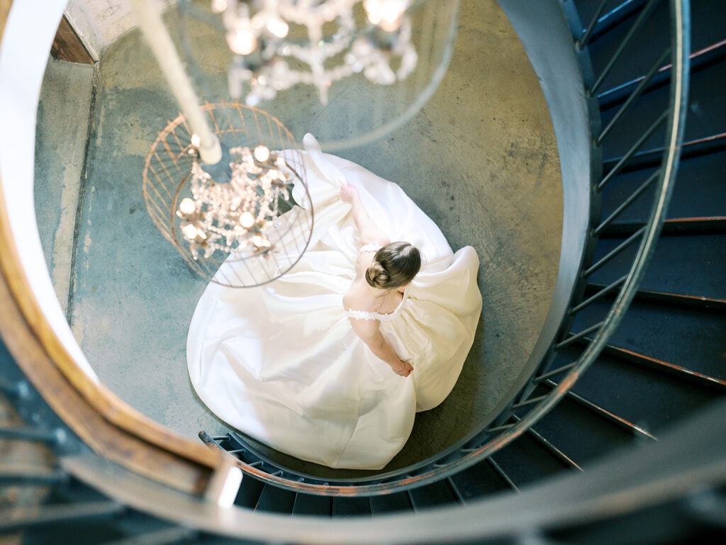 cinematic classy wedding photos of bride spinning a the bottom of spiral staircase