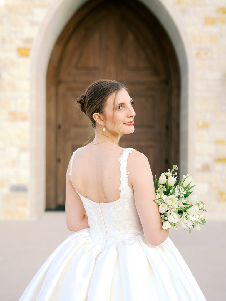 bride looking over her shoulder and smiling in front of the venue entrance