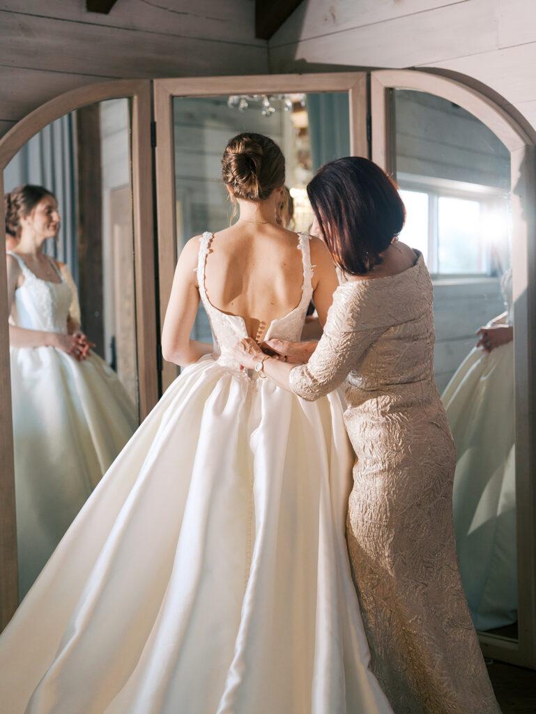 mother of bride helping bride in her dress at the weinberg at wixon valley
