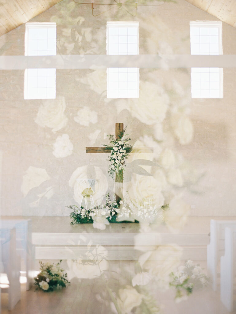double exposure photo of a wedding venue altar with a wood cross decorated with white florals
