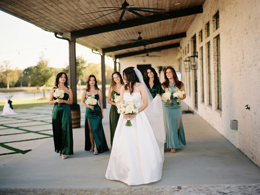 candid photo of bride walking with her bridesmaids wearing green dresses