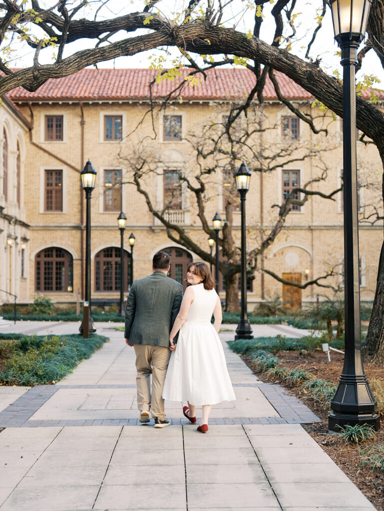couple holding hands and walking on a pathway