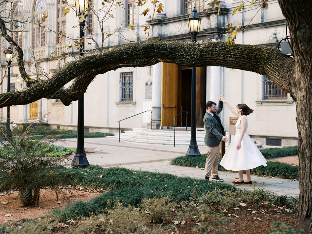 couple spinning underneath a tree in front of a houston library