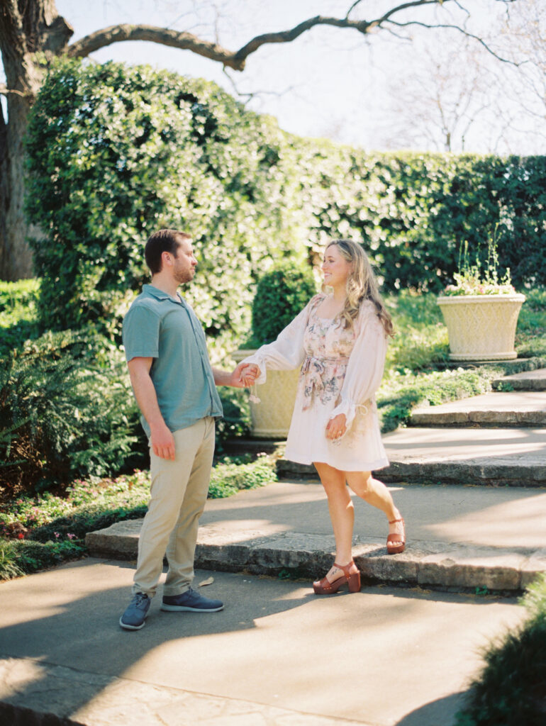 couple holding hands in garden for spring engagement session Dreamy Outdoor Engagement Photos in Botanical Gardens